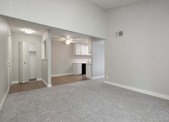 A large, empty room with a carpeted floor and white walls.
