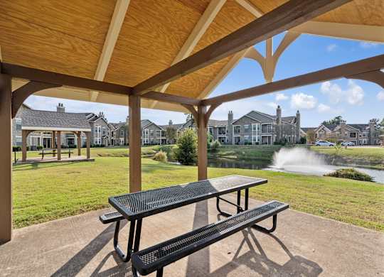 A picnic area with a table and benches under a wooden roof.