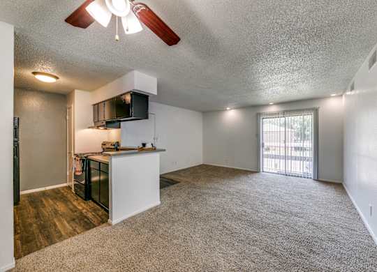 an empty living room and kitchen with a door to a balcony
