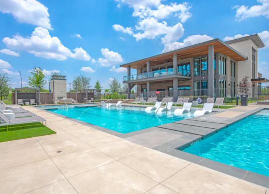 a swimming pool with lounge chairs and a building in the background