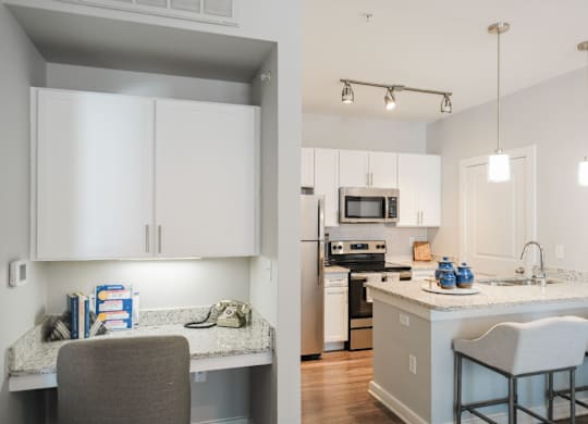 A kitchen with white cabinets and a grey counter.