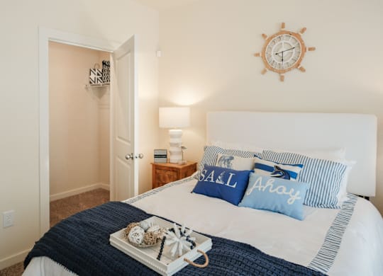 A bedroom with a bed, a clock, and a lamp.