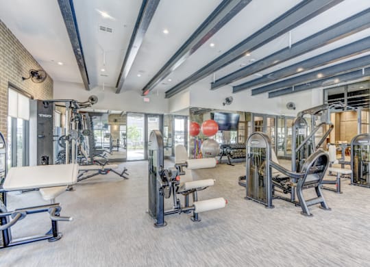 A spacious gym with a variety of equipment including treadmills, weight machines, and free weights.