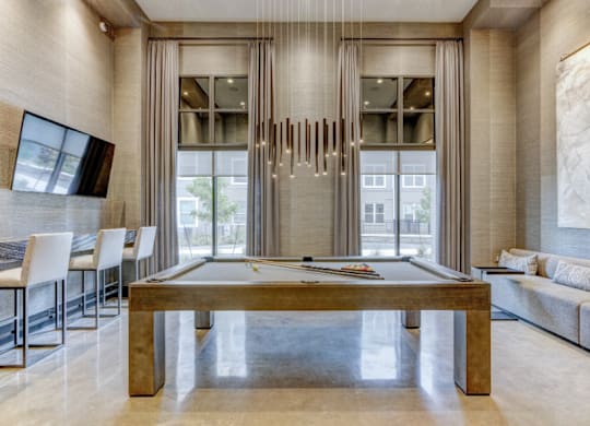 A room with a pool table and a long hanging piece of artwork.