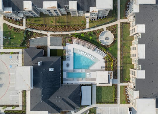 A bird's eye view of a building with a swimming pool in the middle.
