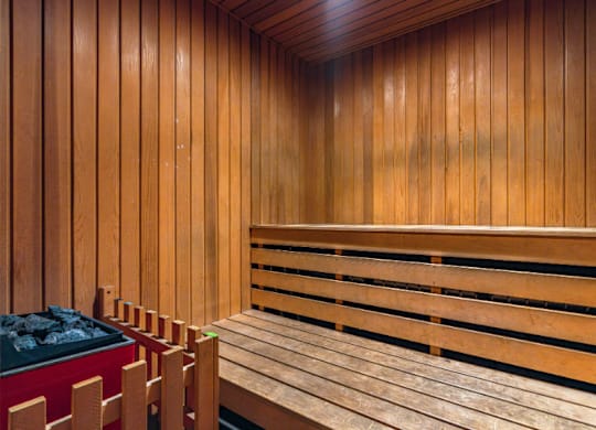 A wooden sauna with benches and a container of coal.