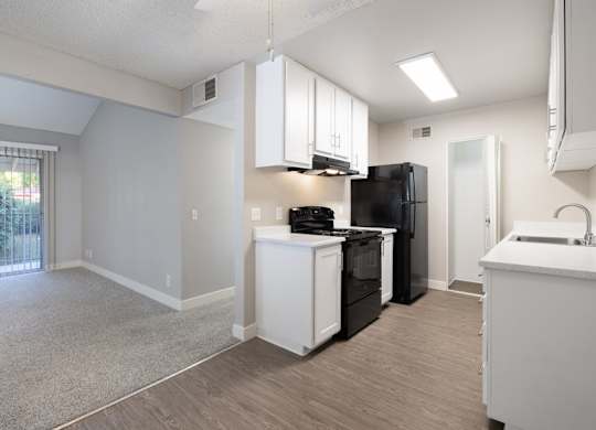 A kitchen with black appliances and white cabinets.