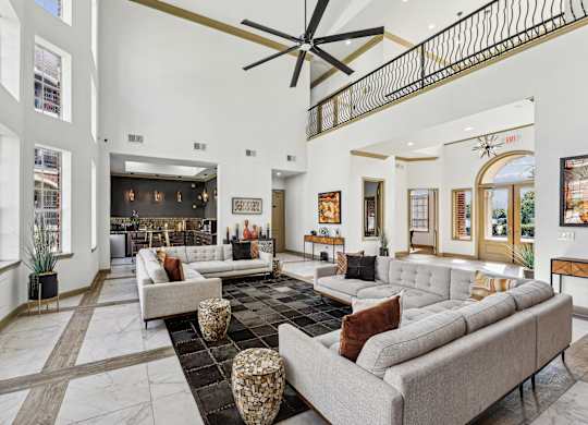 A large, modern living room with a long couch and a ceiling fan.
