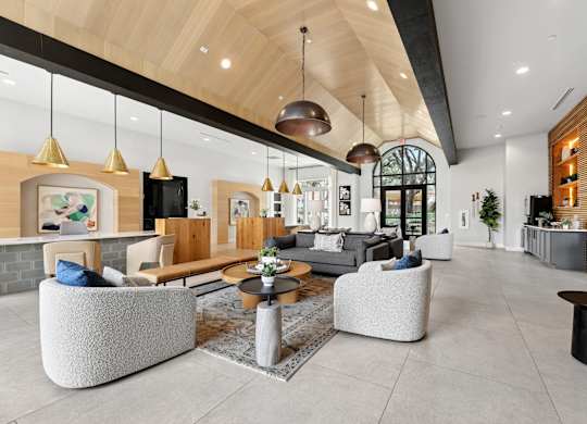 A modern living room with a high ceiling and a mix of furniture styles.