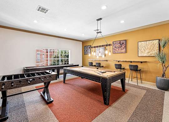 A room with a foosball table and a pool table.