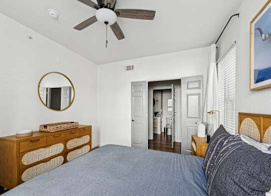 A bedroom with a bed, dresser, and mirror.