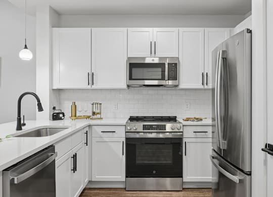 A modern kitchen with white cabinets and stainless steel appliances.