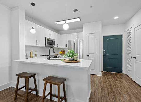 A kitchen with white cabinets and a white island with a plant on it.