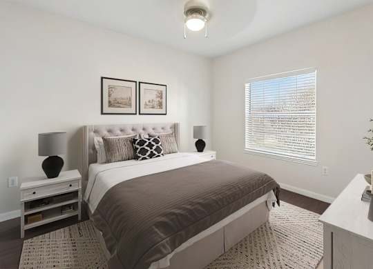 A bedroom with a large bed and a nightstand with a lamp.