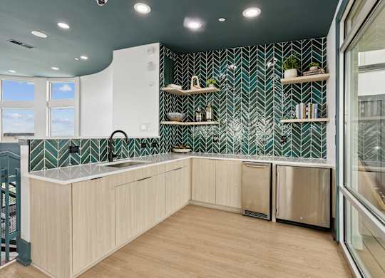 A kitchen with a green and white tiled backsplash and wooden cabinets.