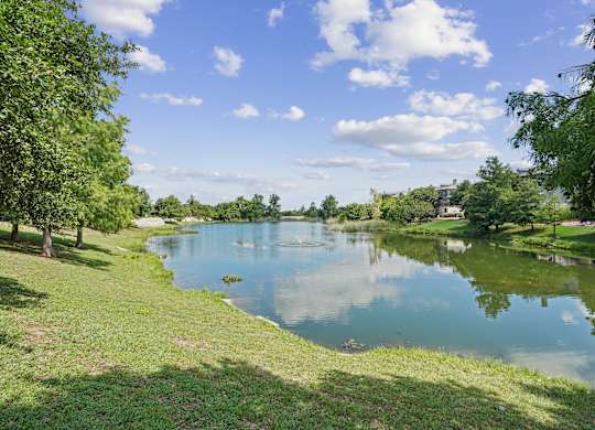 A serene lake surrounded by lush greenery under a clear blue sky.
