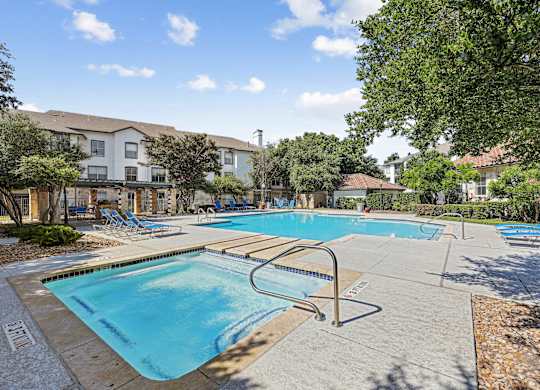A large swimming pool surrounded by trees and chairs.