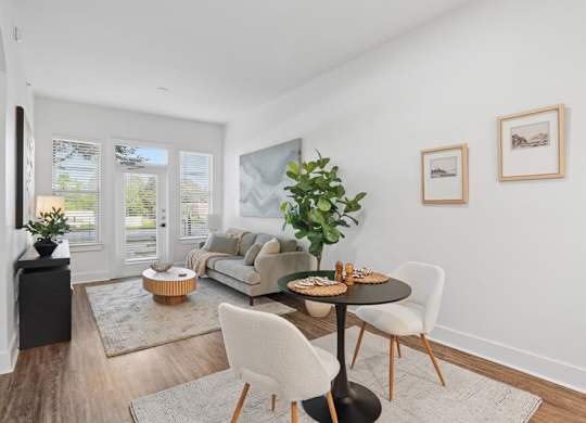 A modern living room with a dining table set for two.