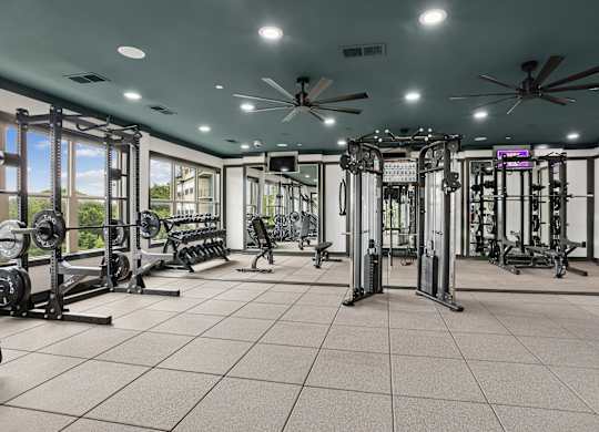 A spacious gym with a variety of equipment and a ceiling fan.