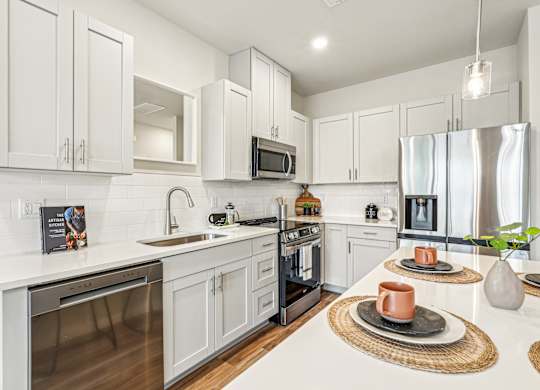 A modern kitchen with white cabinets and stainless steel appliances.
