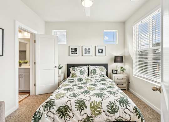 A bedroom with a large bed and a green leaf patterned comforter.