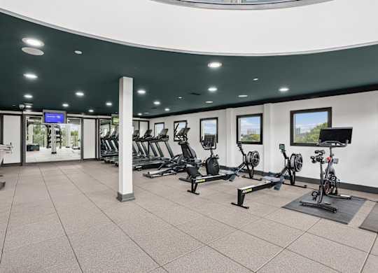 A gym with a variety of equipment including treadmills, stationary bikes, and weight machines.