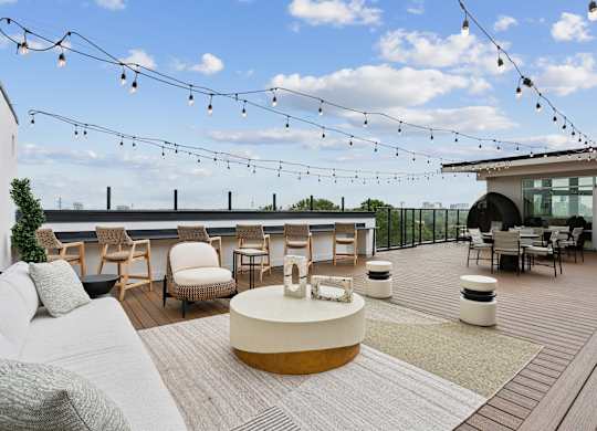 A patio with a white couch and a table with a white bowl on it.