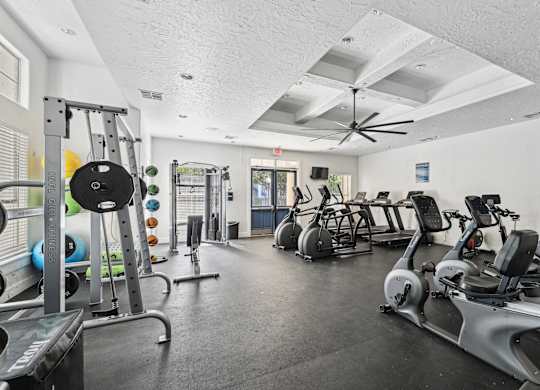 A gym with a variety of exercise equipment including treadmills, stationary bikes, and weight machines.