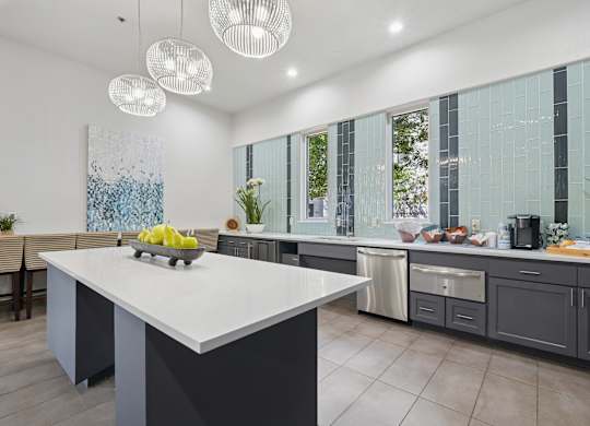 A modern kitchen with a large island and pendant lights.