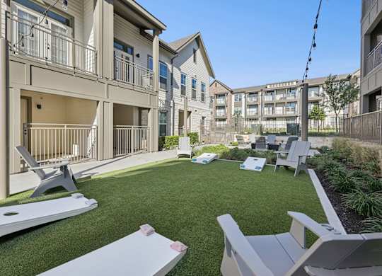 A lawn with chairs and a table in front of apartment buildings.