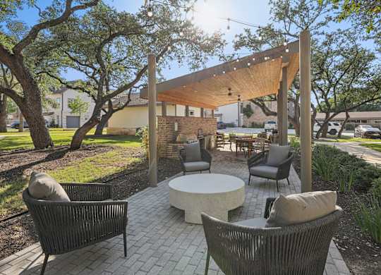 A patio with a table and chairs under a wooden pergola.