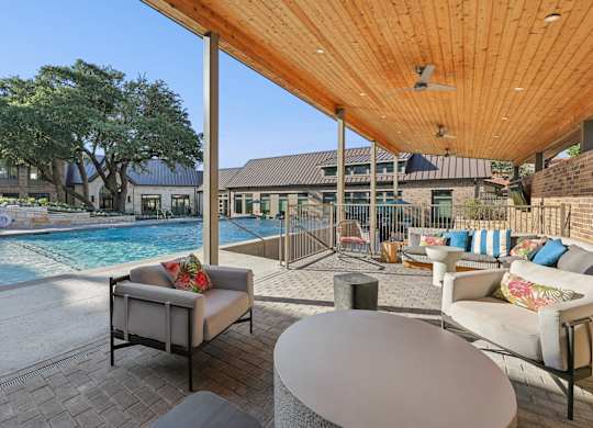 A patio with a table and chairs overlooking a pool.