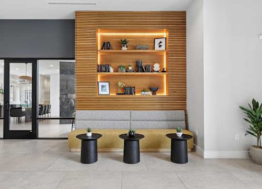 A room with a wooden bookshelf and black stools.