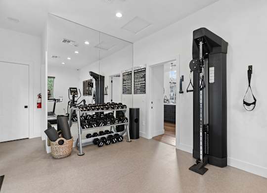 A gym room with a weight rack and a mirror.