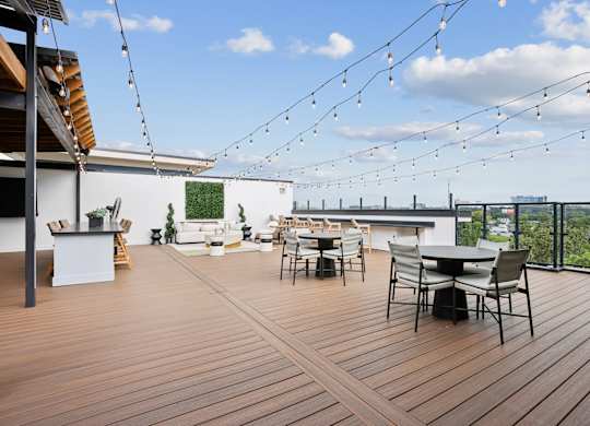 A wooden deck with a table and chairs is set up on a balcony.
