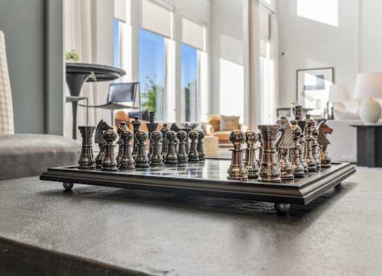 A chess set is on a table in a room with a window.