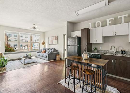 an open living room with a kitchen with a bar and stools