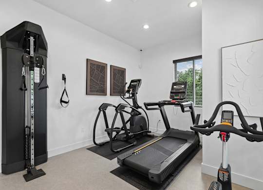A home gym with a treadmill, a stationary bike, and a rowing machine.