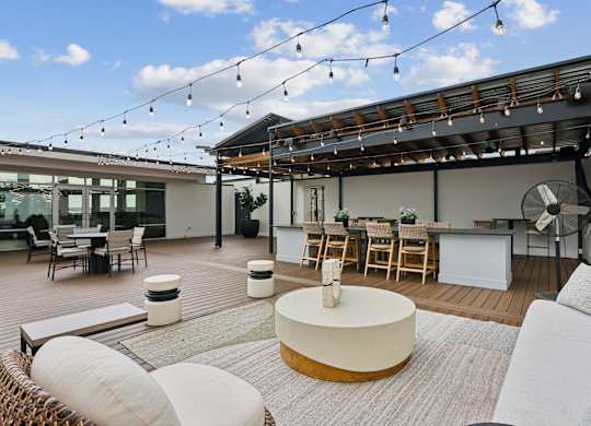 A patio with a white couch, a wooden table, and a ceiling fan.
