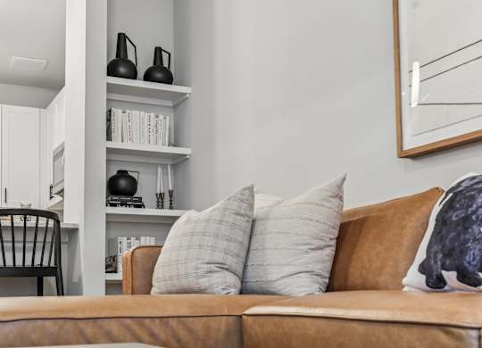 A brown couch with a grey pillow and a black sculpture on it.
