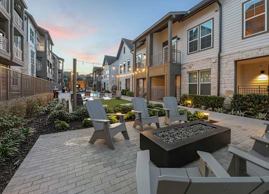 A patio with chairs and a fire pit in the middle of a residential area.