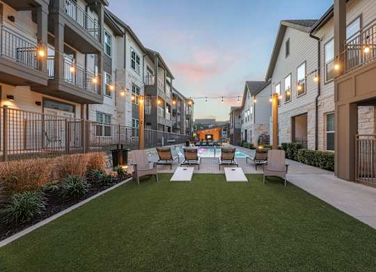 A sunny day at a residential complex with a grassy area and apartment buildings.
