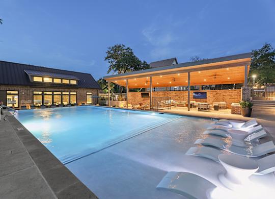A large outdoor swimming pool with loungers and a building in the background.