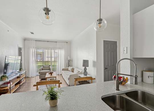 A modern kitchen with a white countertop and a stainless steel sink.
