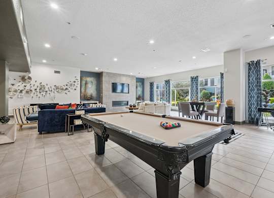 A pool table is in the middle of a room with a blue sofa and a painting on the wall.