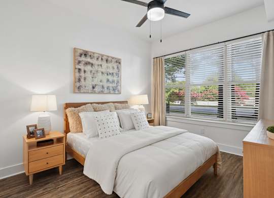 A bedroom with a bed, nightstand, and a ceiling fan.