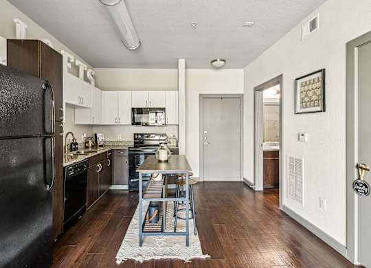 a kitchen with black appliances and a wooden table