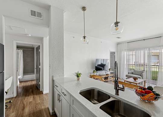 A kitchen with a white counter top and a bowl of fruit on it.