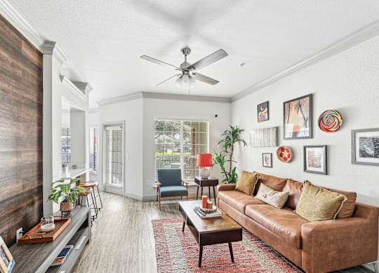 A living room with a brown couch and a ceiling fan.