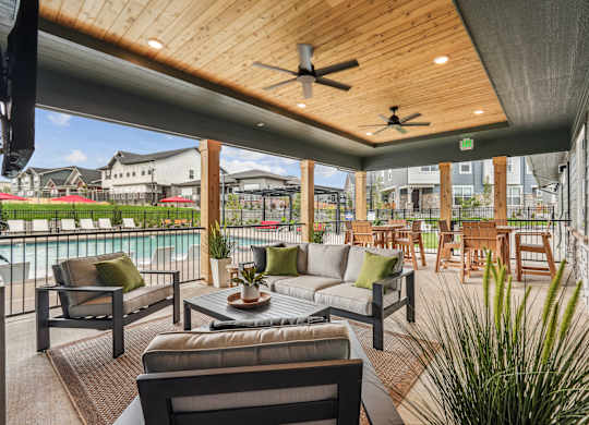 A patio with a couch, chairs, and a table with a potted plant on it.